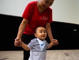 una signora cinese dopo aver finito la ginnastica mattutina a piazza Vittorio gioca con un bambino